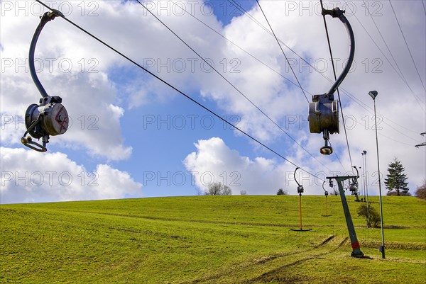 Ski lift at standstill due to lack of snow caused by climate change at the end of winter on a hill in Muensingen