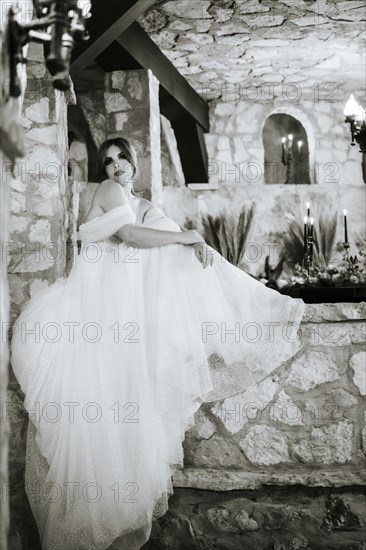 Moody beautiful bride sitting among stone walls