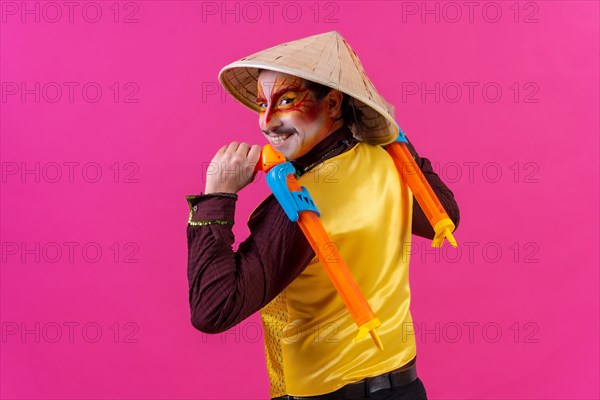 Portrait of a clown with white facial makeup on a pink background