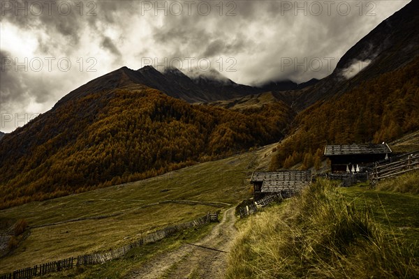 Alpine hut in autumnal mountain landscape with threatening cloudy sky