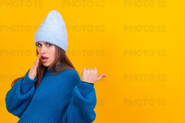 Attractive woman smiling pointing fingers at copy space on yellow background