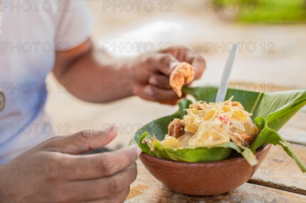 Close-up of person eating vigoron on table. Local person eating a traditional vigoron. The vigoron typical food of Granada
