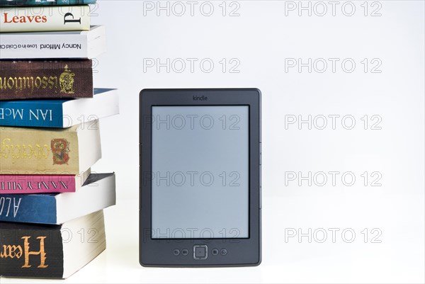 Kindle e reader with a large pile of books