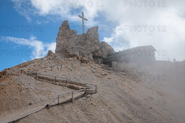 A closed mountain shelter in the Dolomites with a cross towering over it. Dolomites, Italy, Dolomites, Italy, Europe