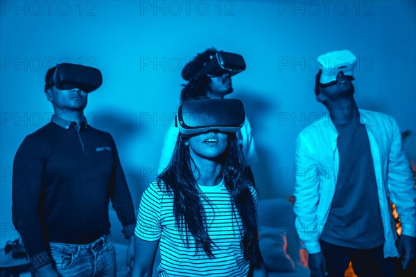 Group of young people with vr glasses in a virtual reality game in a blue light