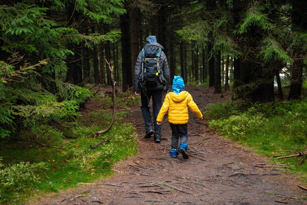 Mum and her little son go on a mountain trail in wet autumn weather. Polish mountains