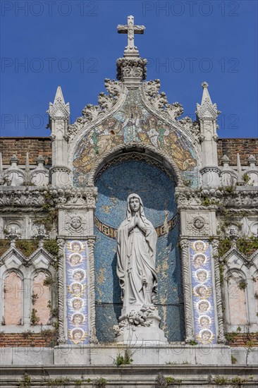 Detail of the top of the facade of the Capuchin Church of Our Lady of Lourdes with a statue of Our Lady of Lourdes decorated with a mosaic