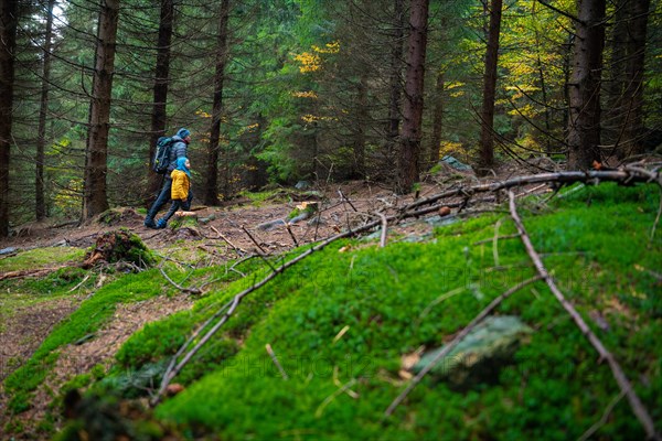 Mum and her little son go on a mountain trail in wet autumn weather. Polish mountains