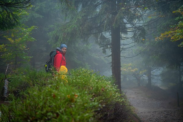 Mum and her little son go on a mountain trail in wet autumn weather.