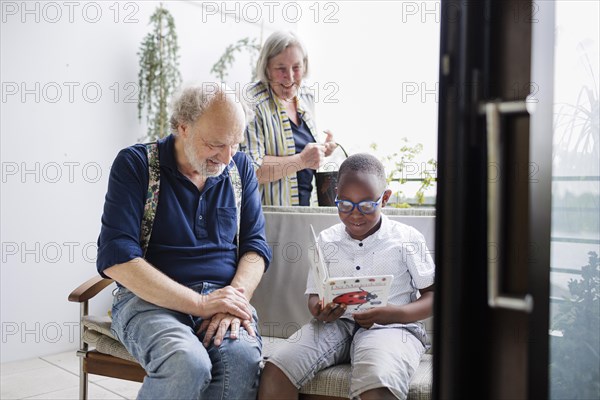Temporary grandparents. Grandfather volunteers to look after a boy from Africa for a few hours a week.