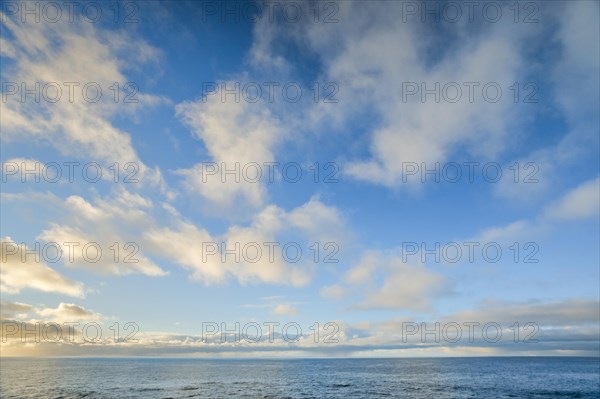 Yellow-white spring clouds in the evening blue sky over the Atlantic Ocean