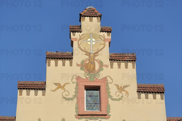 Stepped gable of the historic Deer Pharmacy with mural and stag figure with cross and sun