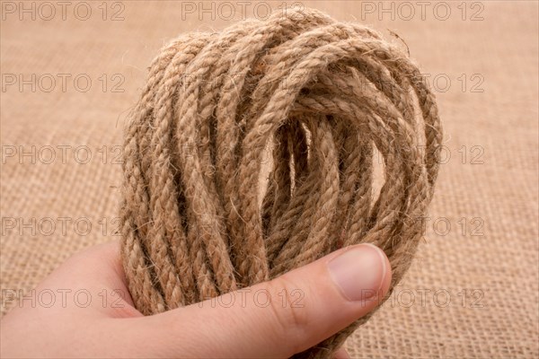 Bundle of linen rope in hand on a brown background