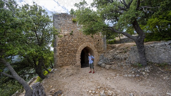 Hikers in front of the tower of the castle ruins Castell Alaro