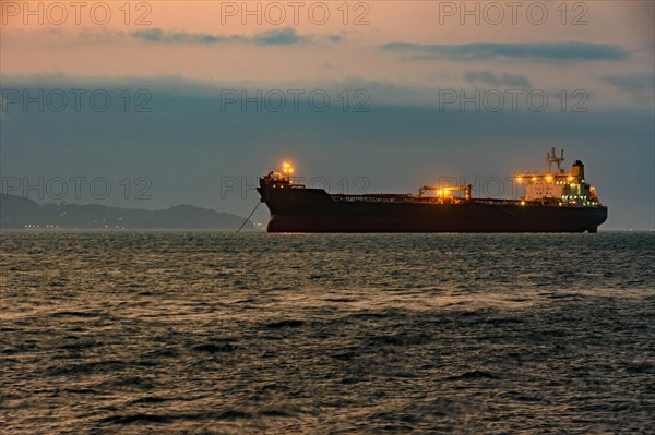 Cargo ship anchored in the waters of Ilhabela Island at dusk with the mountains in the background