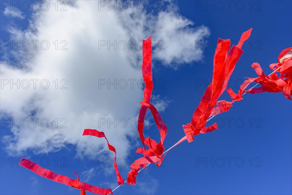 Decorative vivid red ribbons prepared for a religious festival in the city of Lavras Novas in Minas Gerais swaying in the wind with blue sky