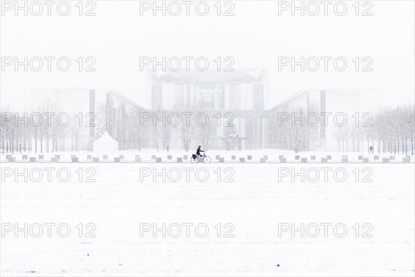 A person is silhouetted in front of the Chancellery in the driving snow in Berlin