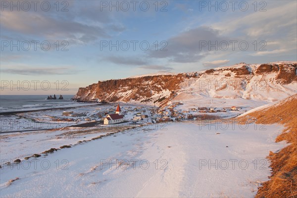 Reynisdrangar sea stacks and the Vik church at the village Vik i Myrdal in winter