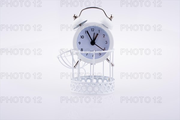 White color alarm clock on bird cage on white background