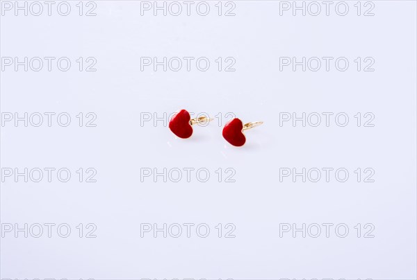 Red color heart shaped earring on white background