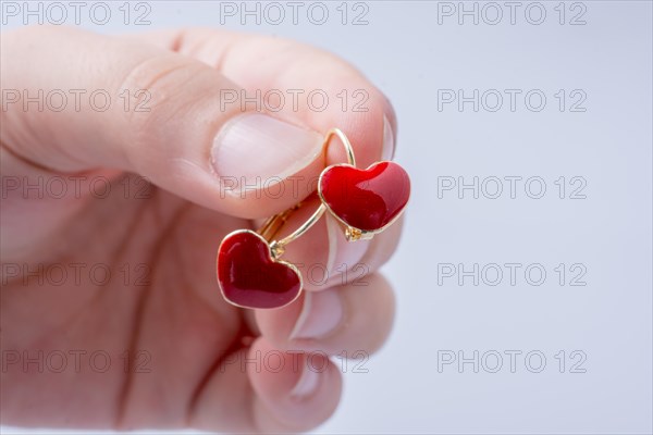 Red color heart shape earring in hand on white