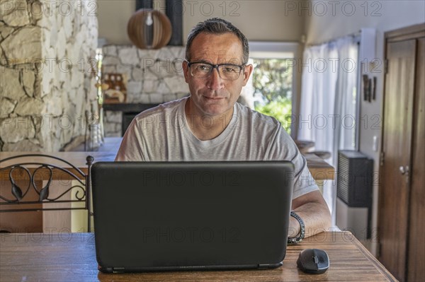Portrait of a good looking man working at home on some project at a table looking at camera