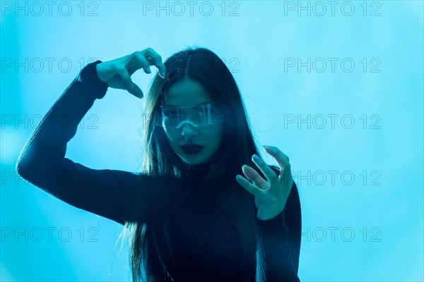 Metaverse technology concept. Woman in futuristic glasses with led light on a blue background