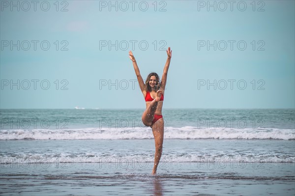 Young woman in red bikini having fun and feeling free in the turquoise sea