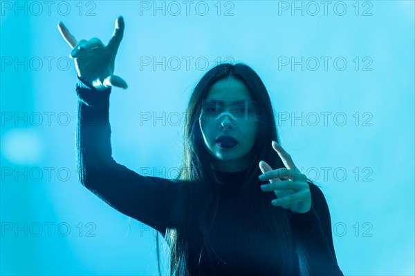 Metaverse technology concept. Portrait of woman in futuristic glasses with led light on a blue background