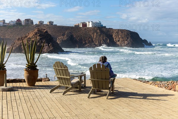 Woman sitting looking out to sea from decking at Hotel auberge Dar Najmat