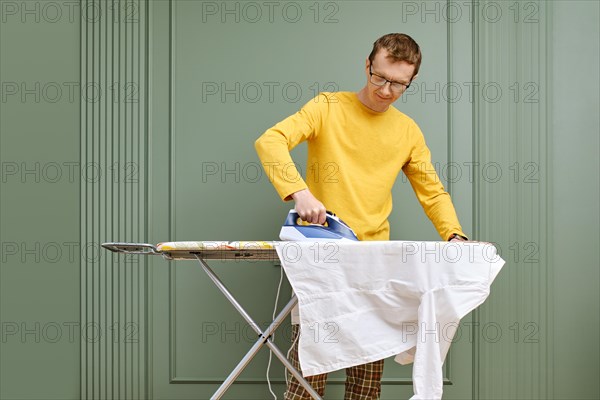 Middle aged man in glasses ironing his shirt