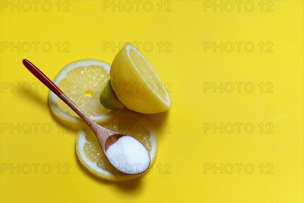 Citric acid in wooden spoon and lemon