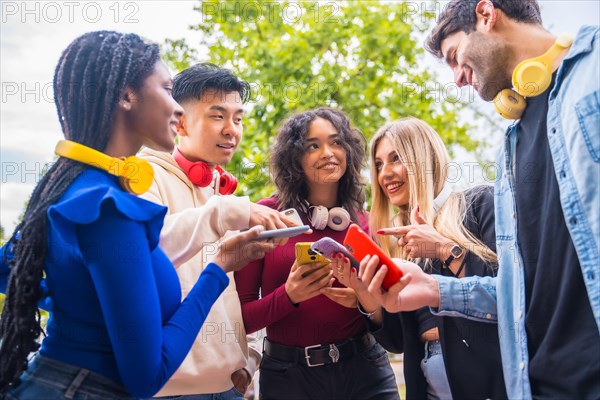 Group of young smiling teenage multiethnic friends using cell phones on campus in the city