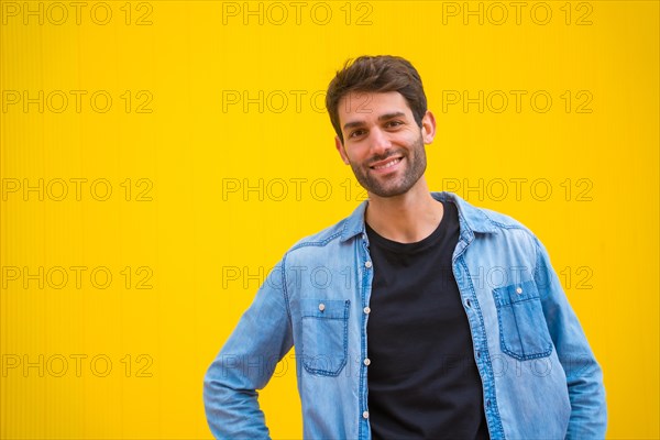 Portrait of an excited handsome man in basic clothes smiling isolated over yellow background