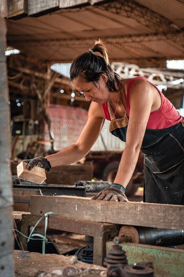 Vertical portrait of a woman with a piece of wood on a cutting machine