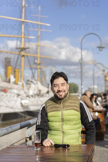 Portrait of a smiling man sitting in a bar at the harbor