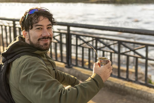 Latin man enjoying the sunset at the river while drinking mate