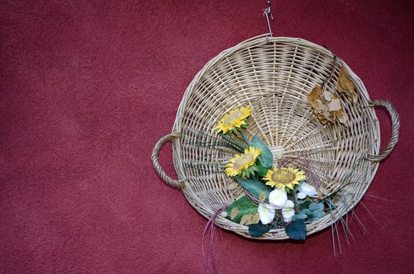 Straw Basket with Flowers Hanging on a Red Wall in Switzerland