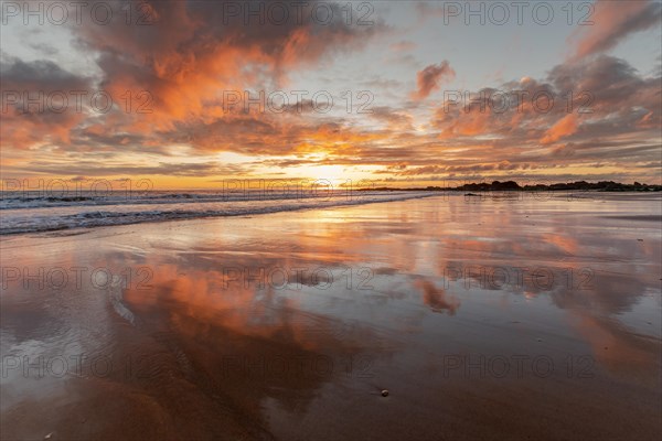 Orange and red sky reflected on the wet sand of an Atlantic beach at sunset. Les Sables-d'Olonne