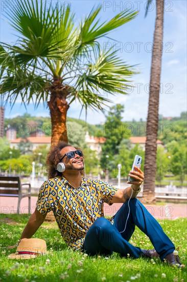 Afro-haired man on summer vacation next to some palm trees by the beach. Travel and tourism concept