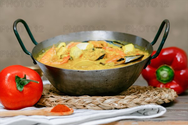 Seafood paella in a metal paella pan served with peppers and fresh tomatoes