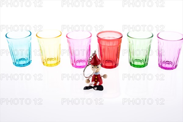 Colorful drinking glass lined up with a doll at the front on white background
