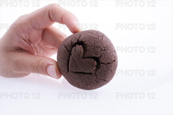 Hand holding a heart patterned chocolate cookie on a white background