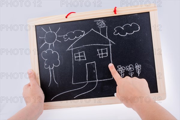 Hand drawing a house on the blackboard with a chalk