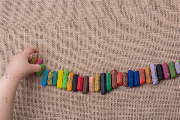 Toddlers hand putting crayons in line on canvas