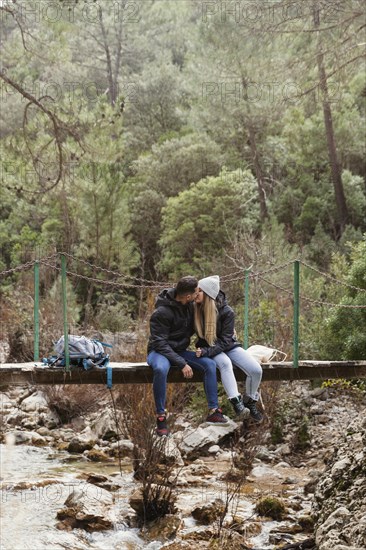 Couple with backpack sitting bridge