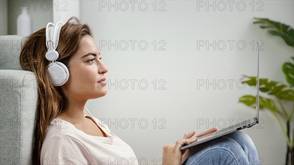 Side view woman with headphones using laptop