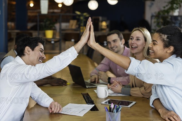 Side view people high fiving each other during office meeting