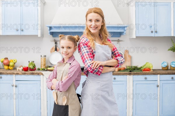 Smiling portrait mother her daughter standing back back with their arms crossed