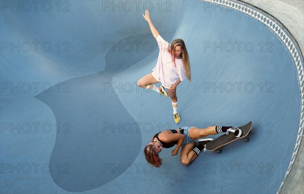 Two female friends having fun skateboarding